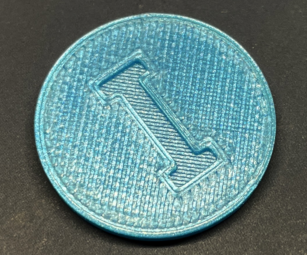 Druckergebnis Vergrößerte Darstellung eines blauen Einkaufswagenchips mit einem eingelassenen I