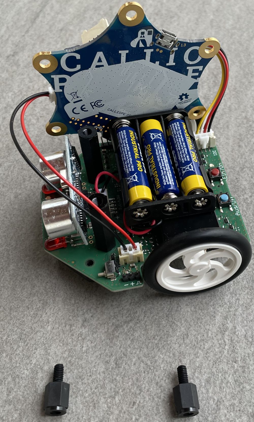 Batteriewechsel Calli:bot mit abgeschraubten aber immer noch per Kabel angeschlossenen Calliope. Der Calliope wurde hochkant an eine Seite gesteckt, so dass das Batteriefach erreichbar ist.